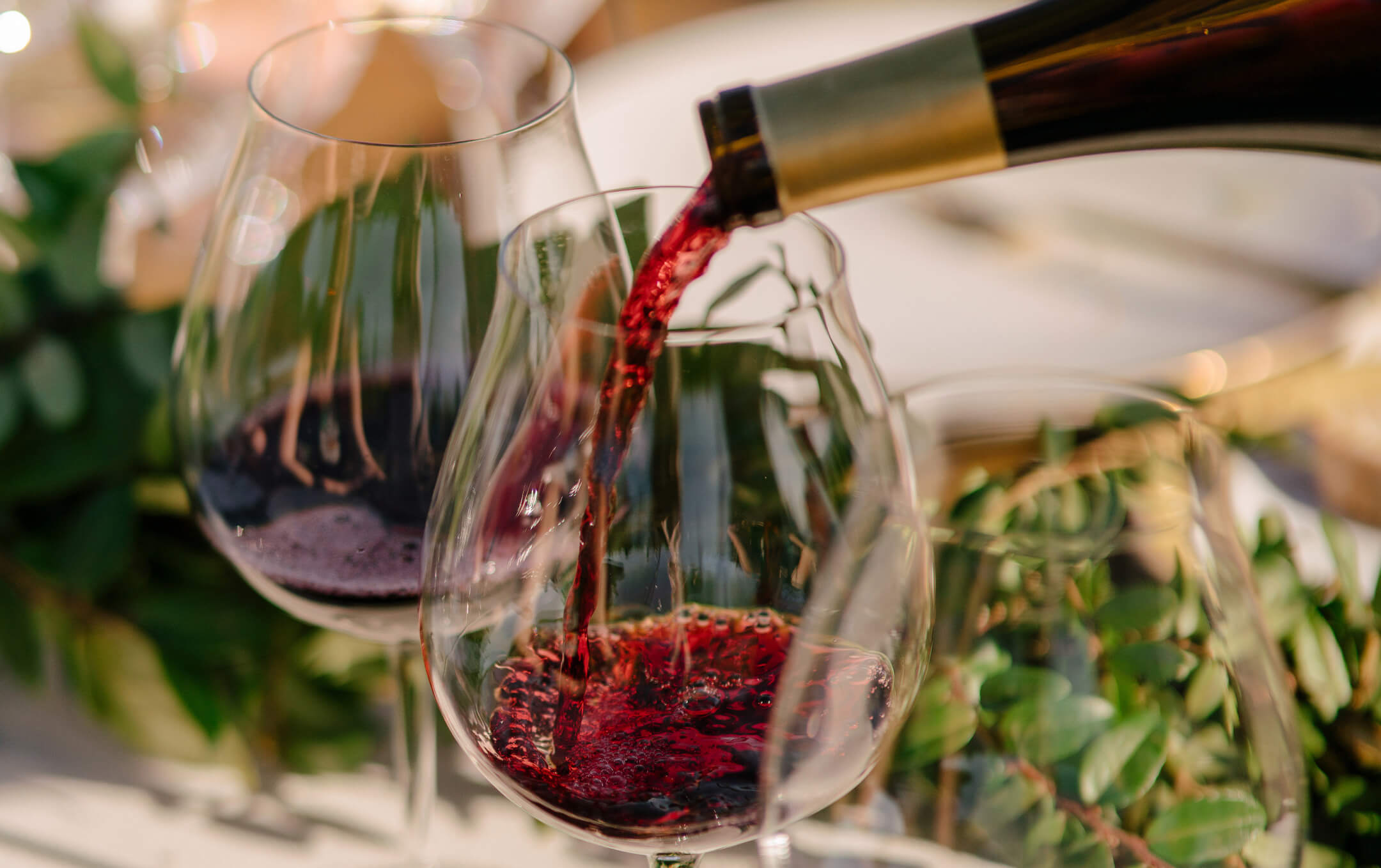 Domaine de Broglie wine being poured into a wine glass at a dinner table. 